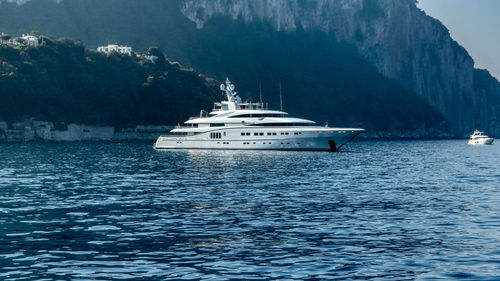 Boat sailing on sea against mountain