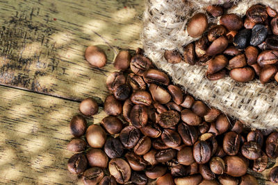 High angle view of roasted coffee bean spilled from jute bag