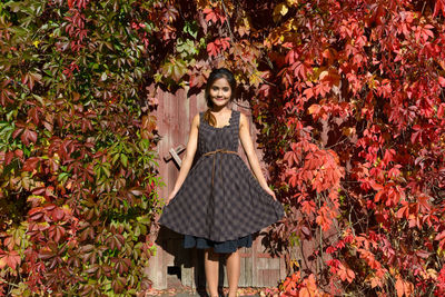 Portrait of smiling young woman standing by plants during autumn