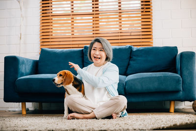 Portrait of woman with dog sitting on sofa at home