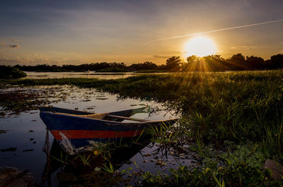 Abandoned boat in lake against sky during sunset