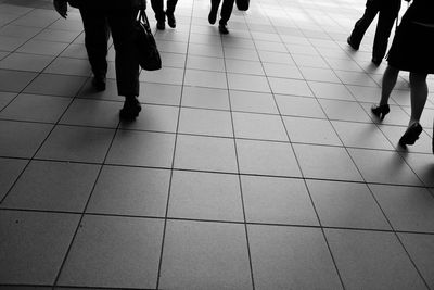 Low section of people walking on tiled floor
