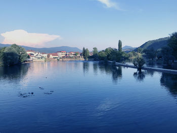 Scenic view of river by mountains against blue sky