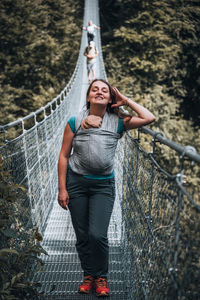 Portrait of smiling woman standing on suspension bridge