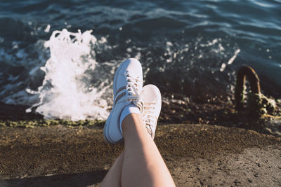 Women's legs in sneakers on the pier in summer
