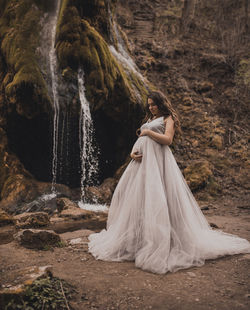 Low section of woman standing against waterfall