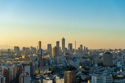 Modern buildings in city against sky during sunset