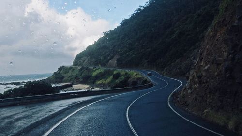 Road by mountains against sky seen through vehicle windshield