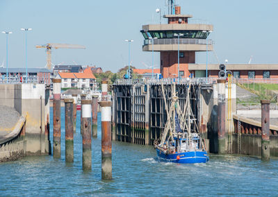 Nautical vessel on sea by buildings against clear sky