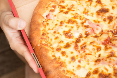 Close-up of hand holding pizza 