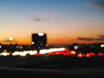 Defocused image of illuminated road against sky at night