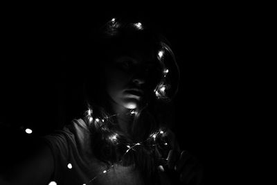 Portrait of woman holding cigarette against black background