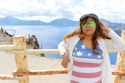 Portrait of young woman standing against mountain range