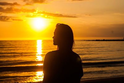 Rear view of silhouette man looking at sea during sunset