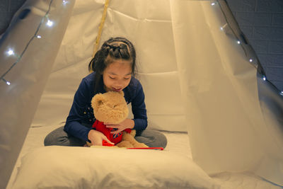 Girl looking away while sitting on bed at home