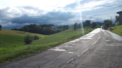 Road amidst field against sky