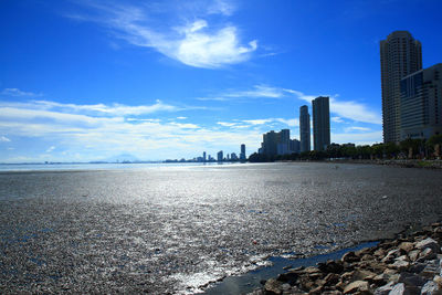 Sea and buildings against blue sky