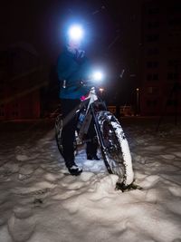 Man riding motorcycle on illuminated street during winter
