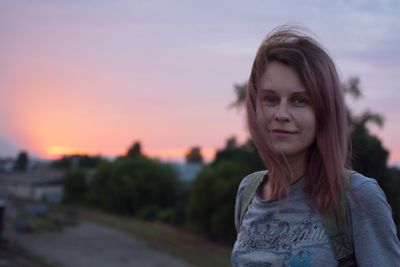 Portrait of smiling woman standing against sky during sunset