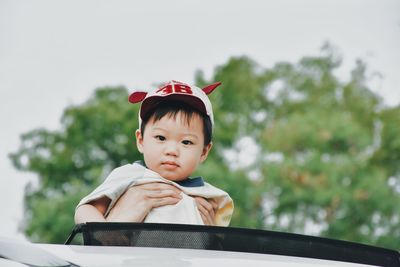 Portrait of cute boy against car