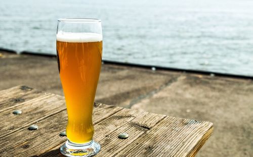 A glass of beer, standing on a wooden table on the quay of ferries on the elbe