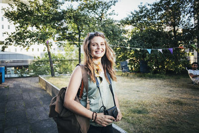 Portrait of smiling young woman against trees