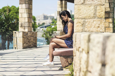 Full length of woman sitting against wall