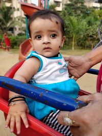 Cropped hand of parent holding daughter sitting on swing