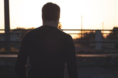 Rear view of man standing against sky during sunset