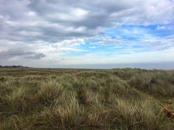 Scenic view of grassy landscape against cloudy sky