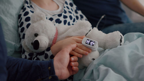 Midsection of woman with stuffed toy on bed