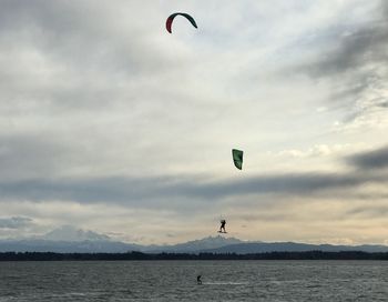 Person paragliding over sea against sky