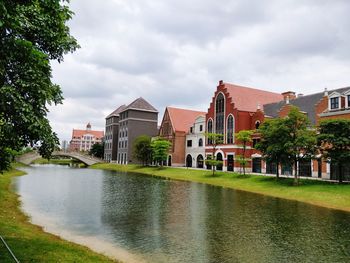 River amidst houses and buildings against sky