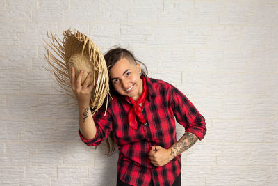 Hipster woman holding hat against wall