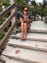 Portrait of woman drinking coconut water while sitting on steps