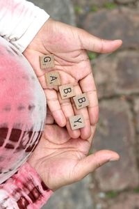 Cropped image of pregnant woman holding wooden alphabets on palm