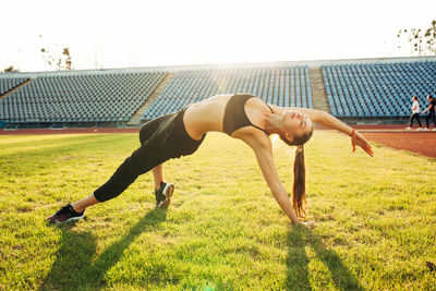 Full length of woman exercising on grass