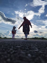 Rear view of couple walking on road against sky