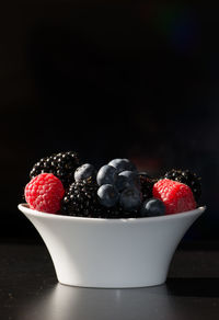 Close-up of strawberries in bowl against black background