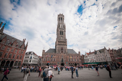 Tourists in front of building against cloudy sky