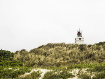 Lighthouse on field against clear sky