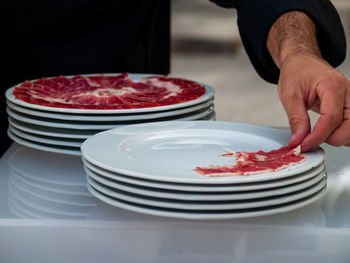 Midsection of male chef arranging meat on plate at table