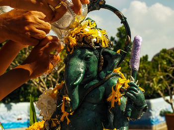 Cropped hands of people pouring water on ganesha