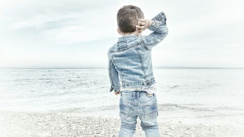 Rear view of boy standing on shore at beach