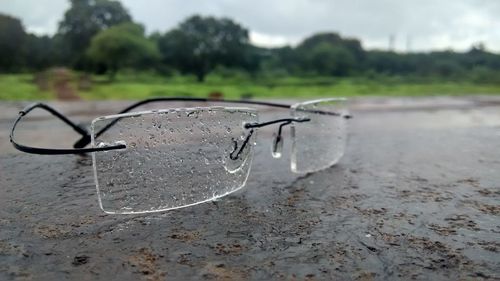 Close-up of eyeglasses on landscape against sky