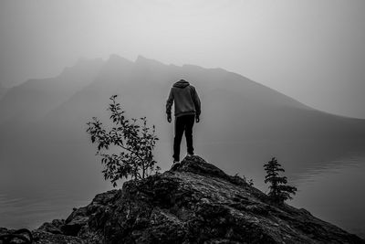 Rear view of man standing on rock against mountain