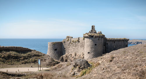 Old building by sea against sky