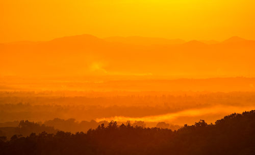 Scenic view of silhouette landscape against orange sky