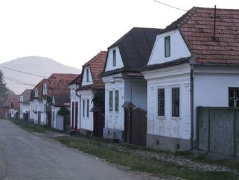 Empty road by buildings against sky
