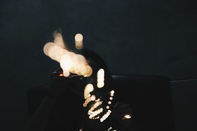 Close-up of hand holding lit candle in the dark